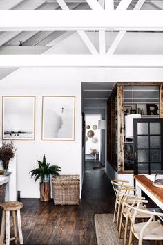 an open kitchen and dining room with wood flooring, white walls and beams on the ceiling