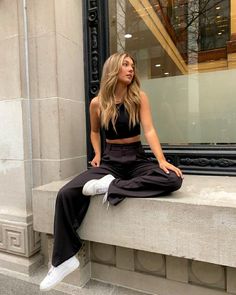 a woman sitting on a window sill with her legs crossed and looking off to the side