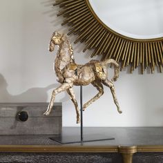 a gold horse statue sitting on top of a wooden table next to a round mirror