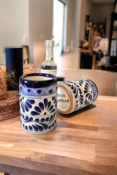 a blue and white cup sitting on top of a wooden table next to a bottle