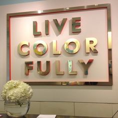 a vase filled with white flowers sitting on top of a table next to a sign that says live color fully