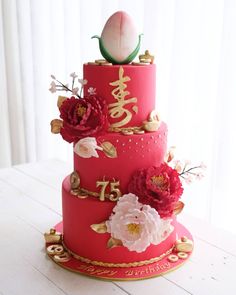 a three tiered red cake with flowers on the top and chinese writing on the side