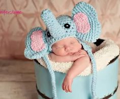 a baby wearing a blue hat with an elephant on it's head sitting in a bucket