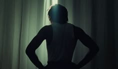 a person standing in front of a curtain with their back turned to the camera,