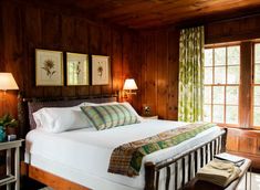 a bedroom with wood paneling and white bedding, two lamps on either side of the bed