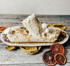 a piece of cake sitting on top of a white plate next to sliced oranges