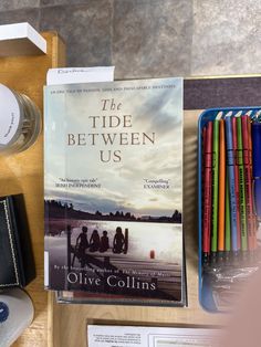 a book sitting on top of a wooden table next to other books and pencils