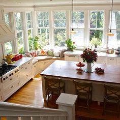 a large kitchen with white cabinets and wooden counter tops, along with an island in the middle