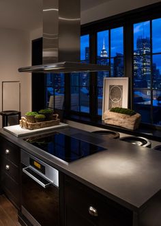 a kitchen with a large window overlooking the city at night, and an island in front of it