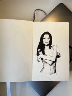 an open book with a drawing of a naked woman