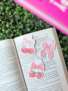 an open book with pink bows and cherries on it