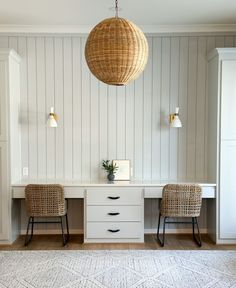 two wicker chairs sitting on top of a white desk next to a light fixture