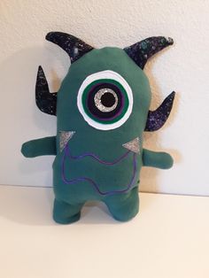 a green stuffed animal with horns and eyes