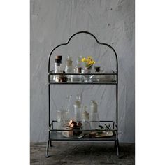 a metal shelf with glass bottles on it and flowers in vases sitting on top