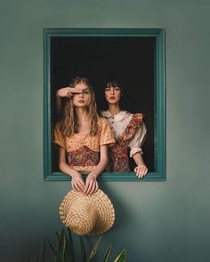 two young women are looking out the window