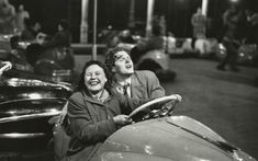 two people sitting in the driver's seat of an old car at night time