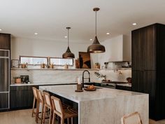 a kitchen with marble counter tops and wooden chairs in front of an island that has stools on it