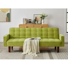 a green couch sitting on top of a rug next to a wooden dresser and window