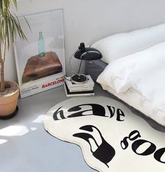 a bed room with a neatly made bed next to a plant and pictures on the wall