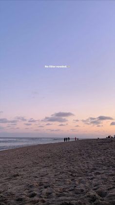 people are walking on the beach at sunset