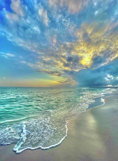 the sun is setting over the ocean with clouds in the sky and water on the beach