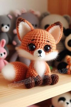 a crocheted fox sitting on top of a shelf next to other stuffed animals