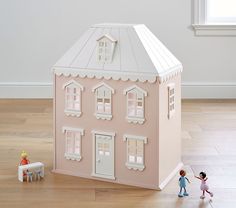 a doll house with two dolls standing in front of it