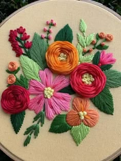 a close up of a embroidery on a piece of cloth with flowers in the center