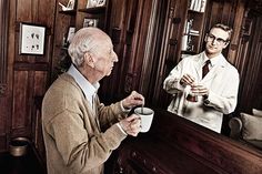 an old man holding a coffee cup in front of a mirror while another man looks at his reflection