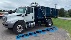 a dump truck parked in a parking lot with the words checking out a new hooklift