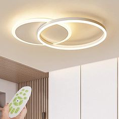 a person is holding a remote control in their hand and the ceiling light has two circular lights above them