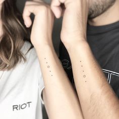 two people with matching tattoos on their arms, one holding the other's arm