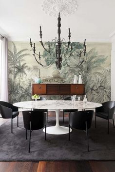 a dining room table with black chairs and a chandelier hanging from the ceiling