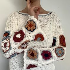 a woman wearing a white sweater with crocheted flowers on it