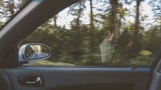 the rear view mirror of a car with trees in the background