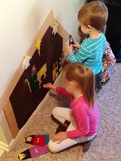 two young children playing with magnets on the floor next to a wall and door