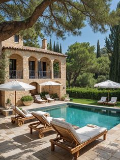 an outdoor swimming pool with chaise lounges and umbrellas in front of it