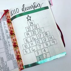 an open planner with numbers on it and a red ribbon around the page that says hello december