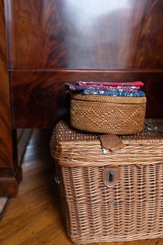 two wicker baskets stacked on top of each other in front of a wooden bed