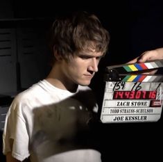 a young man holding a movie clapper in his hand