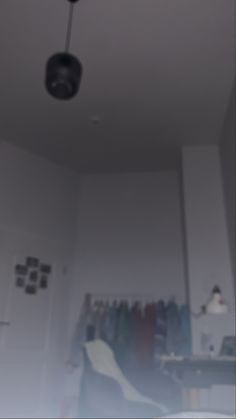 a blurry photo of a room with clothes hanging on the wall and a ceiling fan