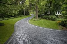 a cobblestone road in the middle of a lush green yard