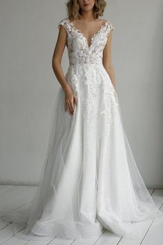 a woman in a white wedding dress standing on a wooden floor next to a wall