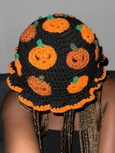 a woman wearing a crocheted hat with pumpkins on it