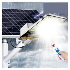 a solar powered street light with the sun shining behind it and someone holding a remote control