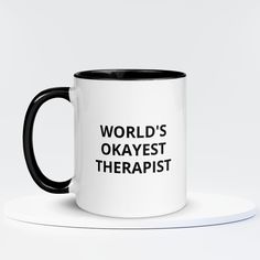 a black and white coffee mug that says world's okayest therapist