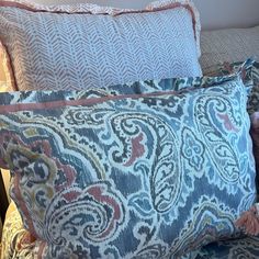 two decorative pillows on a bed with blue and pink patterns, one has a teddy bear