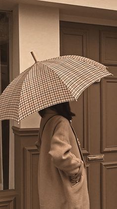 a woman is walking down the street with an umbrella in her hand and she is wearing a trench coat