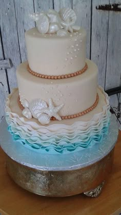 a three tiered cake with seashells on top