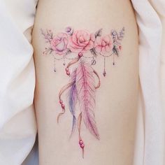 a woman's thigh with flowers and feathers on it